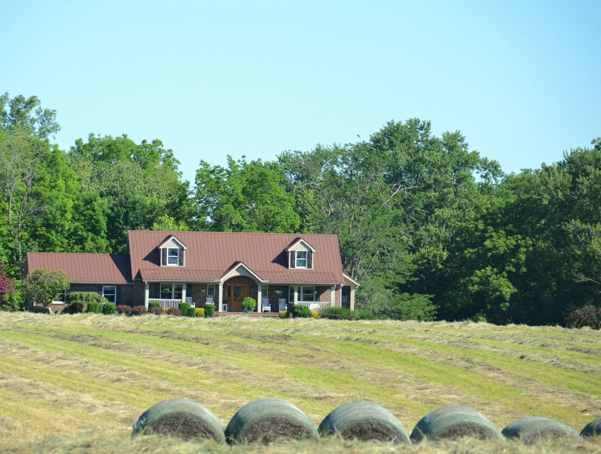 A farmhouse on open land with trees