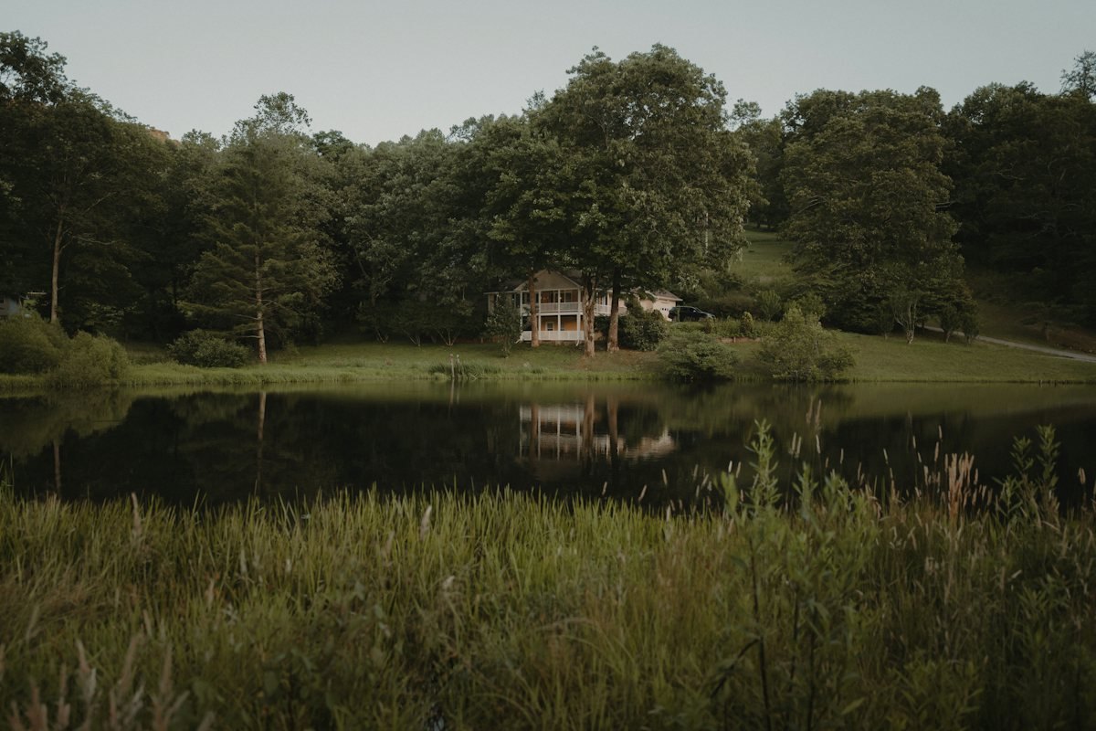 A home across a dam, framed by trees